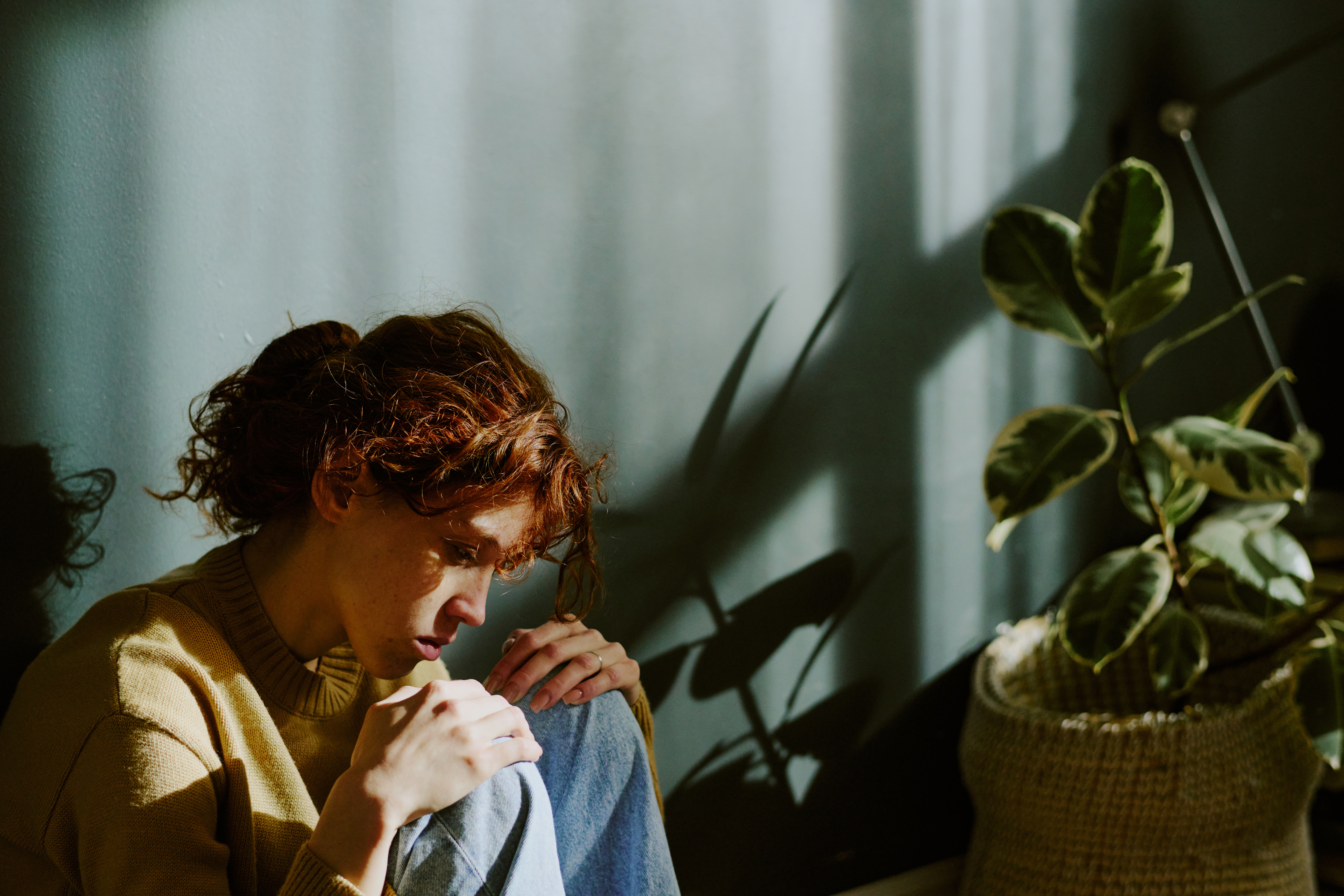 Contemplating Woman Sitting Next to Houseplant Indoors